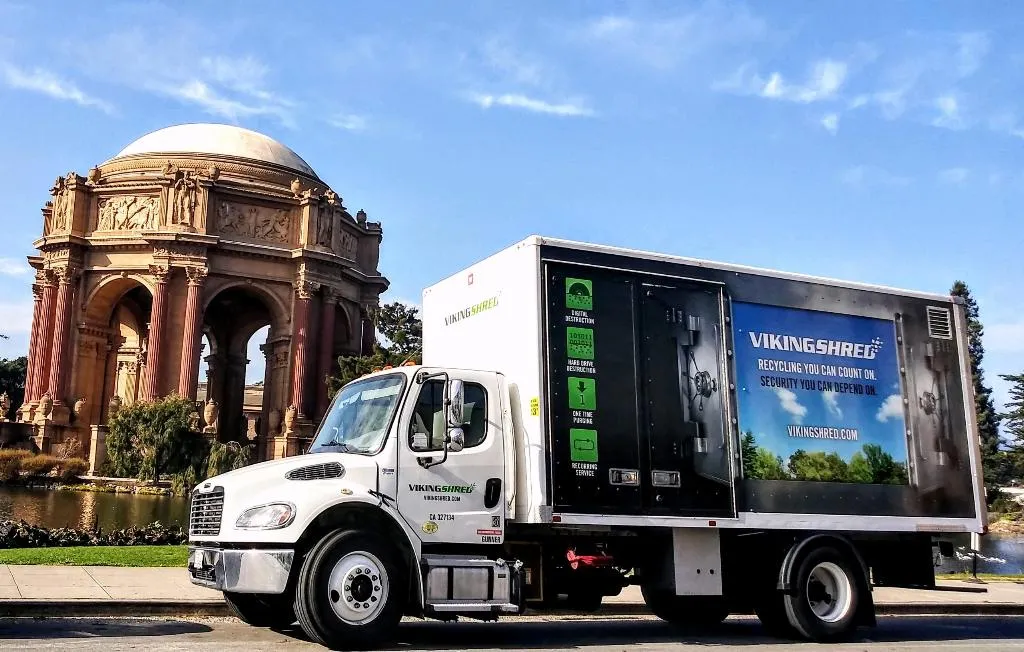 A white truck displaying a large advertisement billboard on its side, parked on a city street.