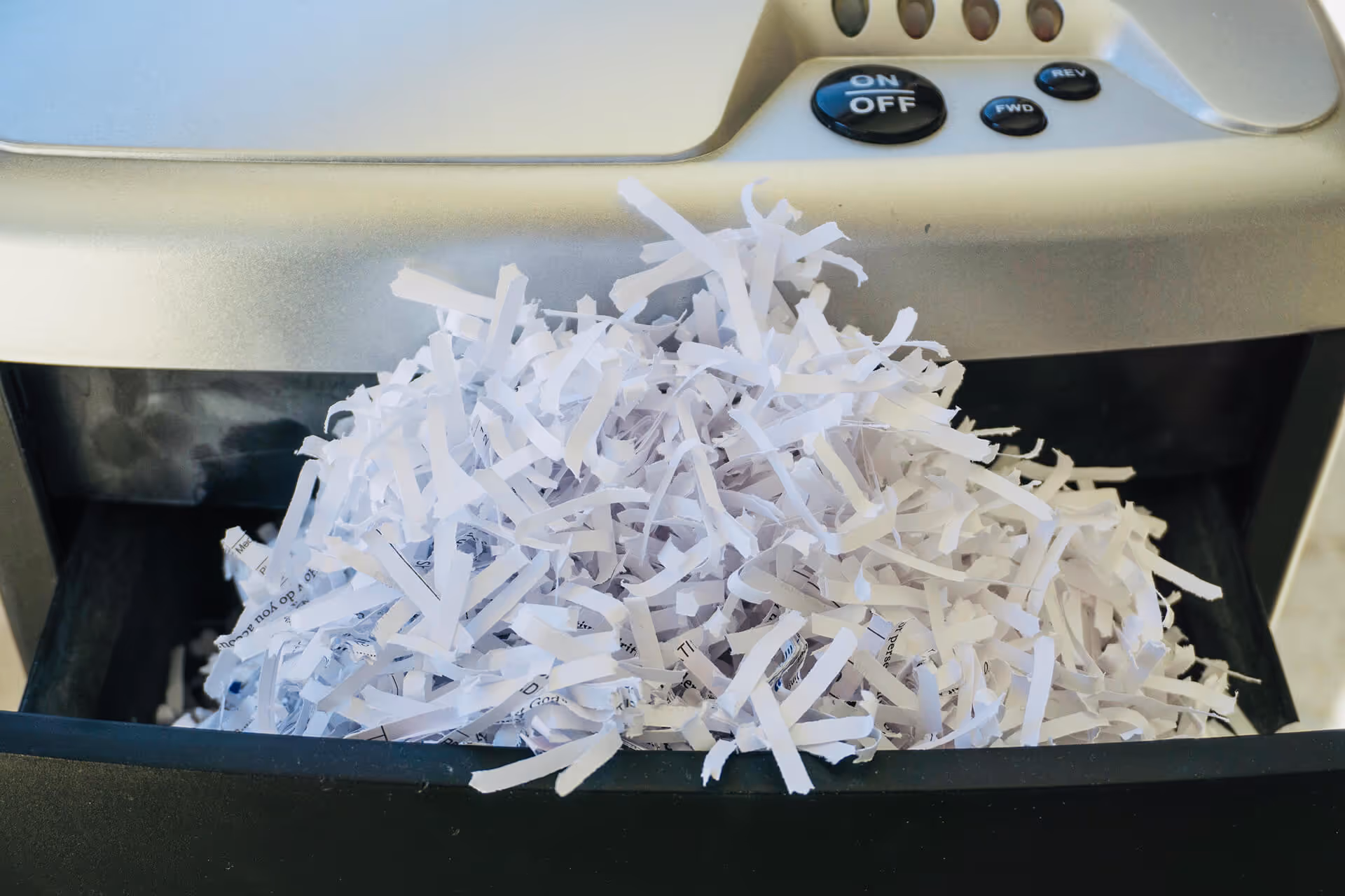 Shredded paper overflowing from an industrial paper shredder.