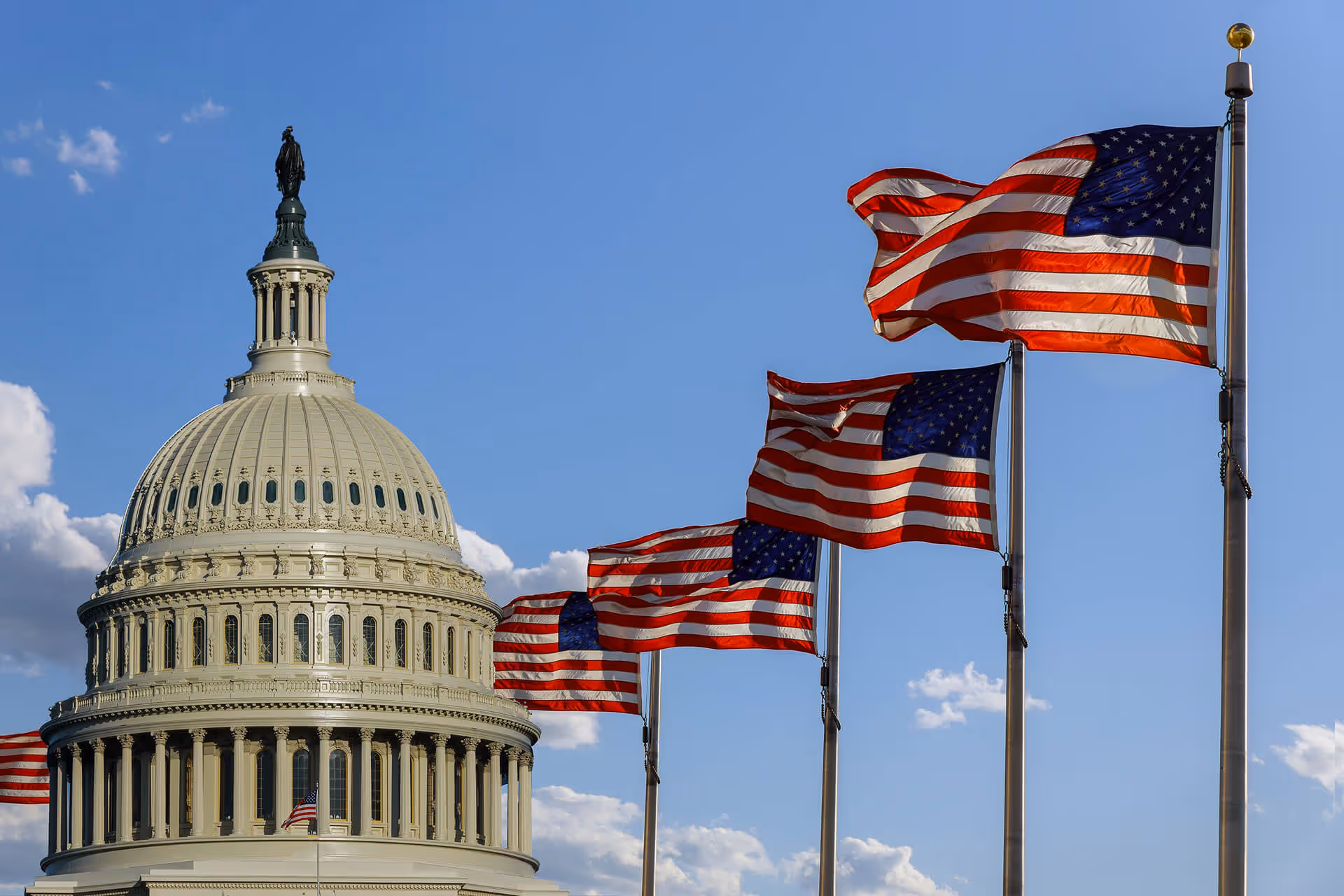 The United States Capitol building dome with American flags in the foreground.