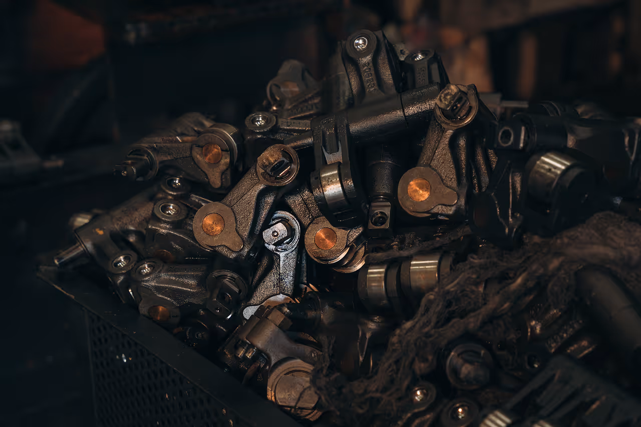 Pile of heavy-duty black metal mechanical components and engine parts in a storage bin.