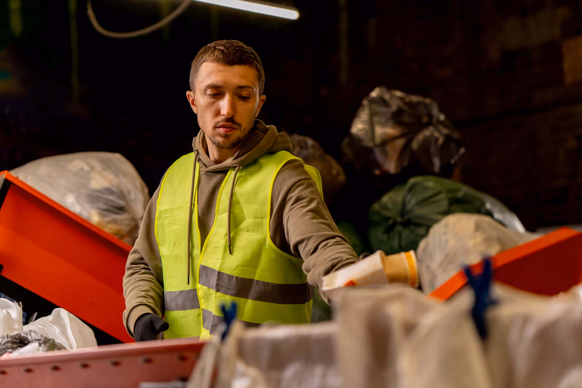 A waste management worker sorting recyclable materials at a facility.