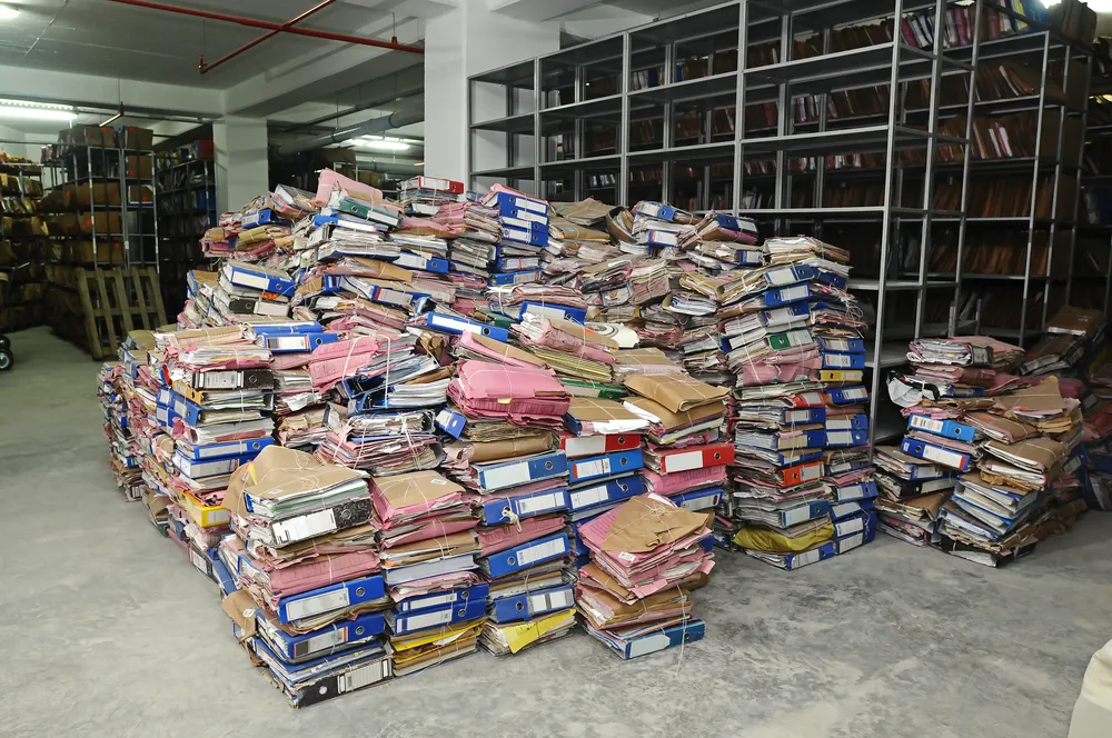A towering stack of books in a warehouse, highlighting the diversity of genres and sizes.