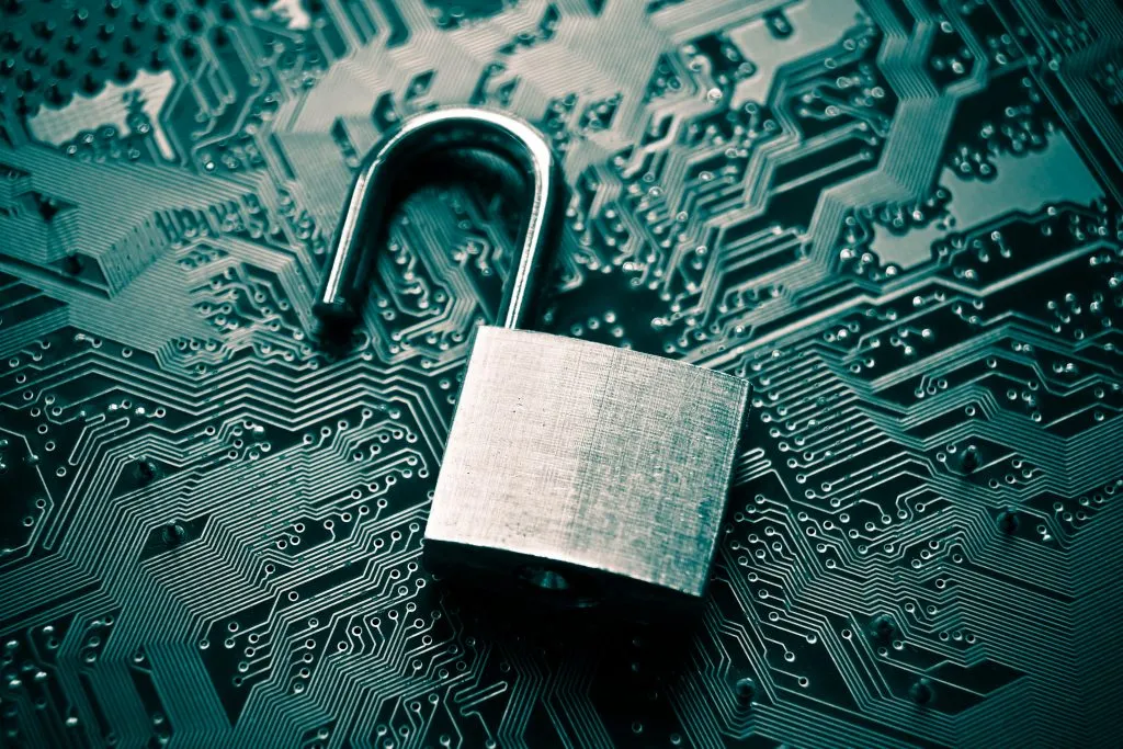 A silver open padlock resting on a dark teal circuit board, symbolizing data security.
