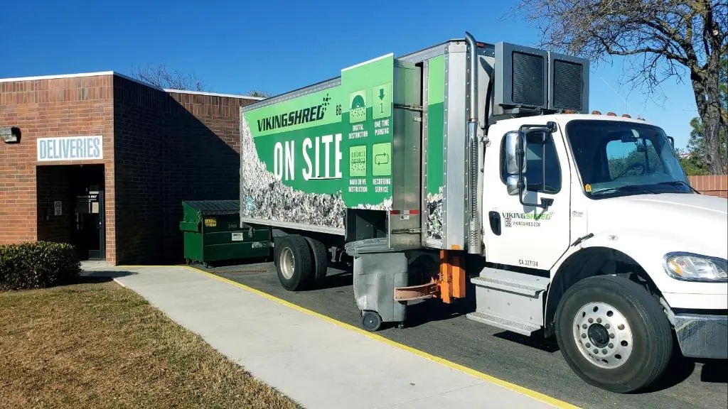 A garbage truck positioned in front of a building, illustrating urban waste disposal services.
