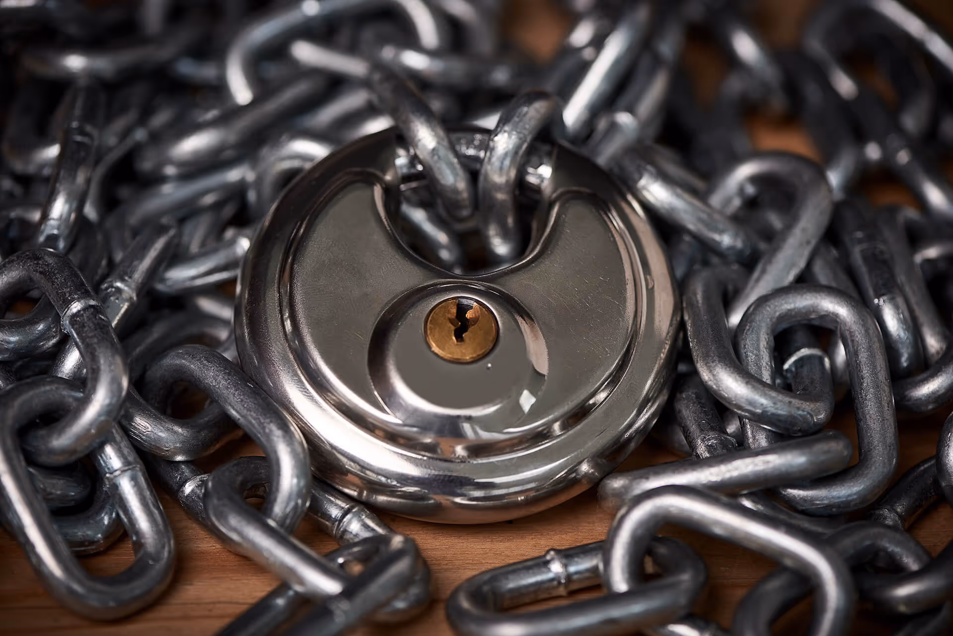 A heavy-duty padlock securing a thick metal chain on a wooden surface.